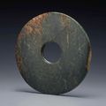 A large mottled dark green jade bi, Neolithic period, North-West China, circa 2000-1500 BC