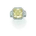 Bague en or gris ornée d'un important diamant jaune de 14.29 carats taille radiant épaulé de deux diamants baguettes