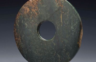 A large mottled dark green jade bi, Neolithic period, North-West China, circa 2000-1500 BC