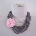 Collier écharpe en chaînettes grises avec broche fleur crochetée rose.