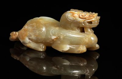 A very rare pale green and russet jade carving of a bixie, Six Dynasties (265-589 AD)
