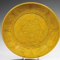 CHINE. Grand plat rond en biscuit émaillé jaune. Début du XXe siècle