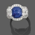 Bague en or gris, ornée au centre d'un saphir coussin épaulé de deux diamants taille émeraude, entouré de petits diamants