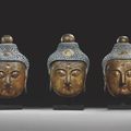 Trois rares tètes monumentales de Bouddha en stuc polychrome et doré. Chine, Dynastie Ming, XVème-XVIème siècle