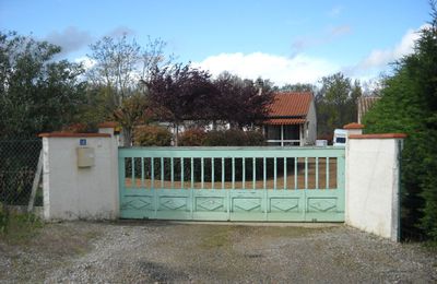 Maison avec un grand portail vert.