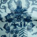 Plat en porcelaine en camaïeu bleu à décor d'oiseau sur un rocher, guirlandes et armoiries. Chine, période Kangxi.. 