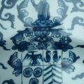 Plat en porcelaine en camaïeu bleu à décor d'oiseau sur un rocher, guirlandes et armoiries. Chine, période Kangxi.. 