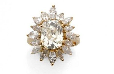 Bague en or jaune sertie d'un diamant taillé en coussin dans un entourage de diamant taillé en navette.