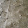 De petits points pour fixer la toile de jute aux