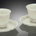 A fine and rare pair of white jade wine cups and quatrefoil stands, Qianlong period (1736-1795)