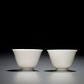 A fine and very rare pair of white-glazed anhua-decorated 'Floral' wine cups, Kangxi six-character marks within double circles a