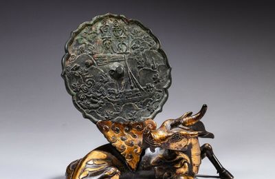 A parcel-gilt bronze 'xiniu' mirror stand and an archaic bronze mirror; the stand, Ming dynasty, the mirror, 12th - 14th century