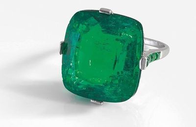 A diamond, onyx, Colombian emerald and platinum ring by Cartier set with a cushion shaped emerald weighing 27,82 cts, ca 1930